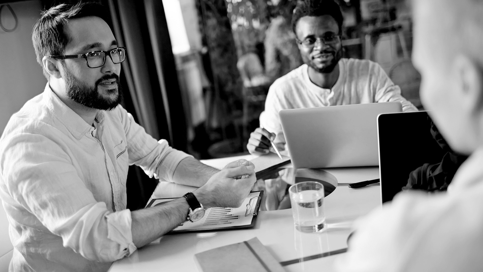 Building capabilities-Three men gathered around a table in black and white