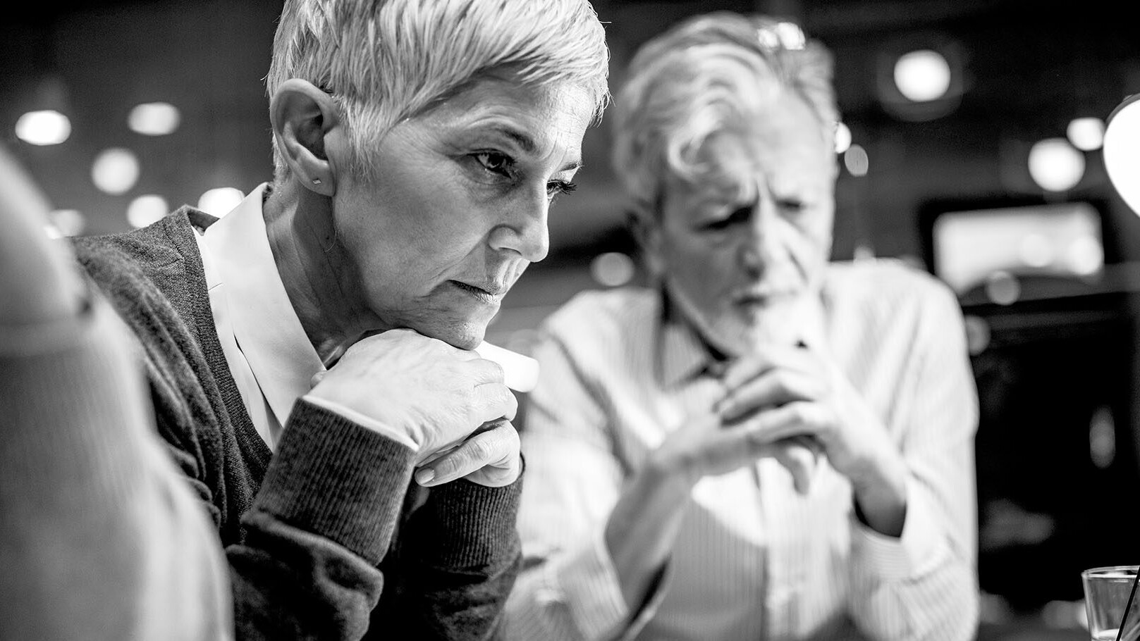 response-Women sitting with chin propped on intercrossed hands looking at a computer with colleagues